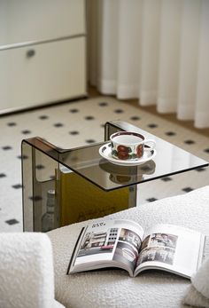 a glass table with a magazine on it and a coffee cup sitting on top of it