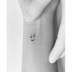 a small smiley face tattoo on the left inner arm, with two eyes and one nose