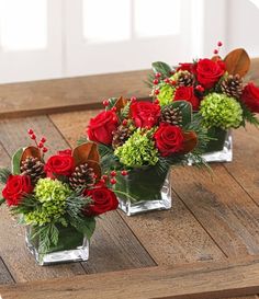 three clear vases filled with red roses and greenery