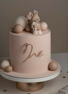 there is a pink cake with an animal on top and the word one written in gold