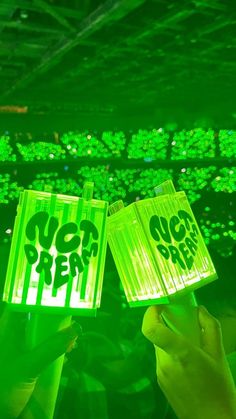 two people holding up signs that say luck and prosperity in front of green lights on the ceiling