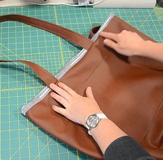 a woman is working on a brown purse