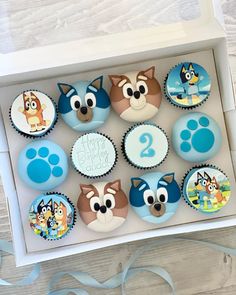 cupcakes in a box with blue frosting and paw patrol images on them