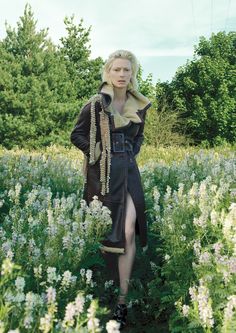 a woman is standing in a field with flowers