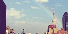 a rainbow is in the sky over a cityscape with tall buildings and skyscrapers