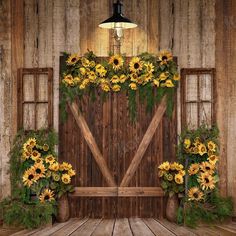 an old barn with sunflowers and greenery on the front door to it