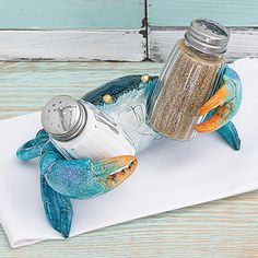 a salt and pepper shaker sitting on top of a white napkin next to a blue crab