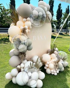 an arrangement of balloons and other decorations on the grass in front of a large sign