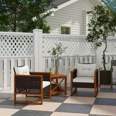 an outdoor sitting area with chairs, table and potted tree