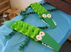 two crocodiles made out of paper sitting on top of a table