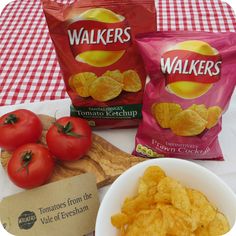 two bags of walkers tortilla chips next to a bowl of tomatoes and some potato chips