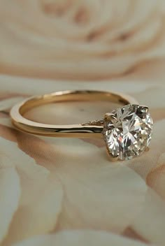 a diamond ring sitting on top of a flowered cloth with the center stone missing