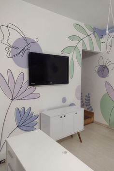 a flat screen tv mounted to the side of a wall next to a white dresser