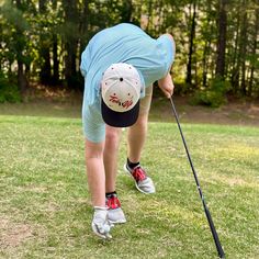 a man bending over to hit a golf ball