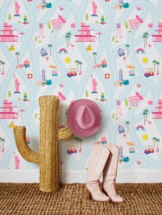 a pink cowboy hat sitting on top of a wooden cactus next to a wallpaper