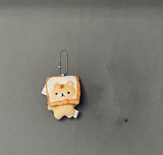 a piece of toast with a bear on it hanging from a keychain that is attached to a wall