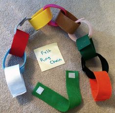 a bunch of different colored wristbands sitting on the floor next to a sign that says felt ring chain