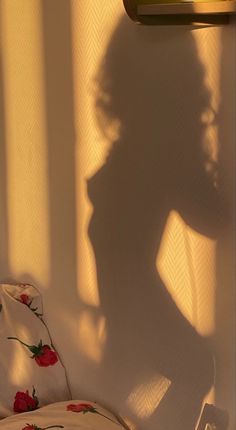 the shadow of a woman's head on a wall next to a bed with white sheets