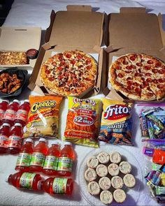 pizzas, snacks and condiments laid out on a bed