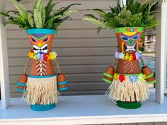 two tiki vases with plants in them on a table next to a pool