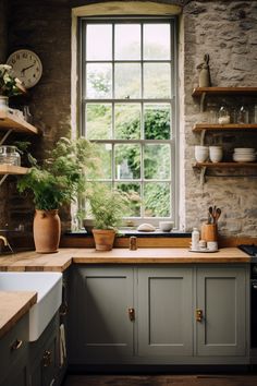 a kitchen filled with lots of counter top space next to a window covered in potted plants