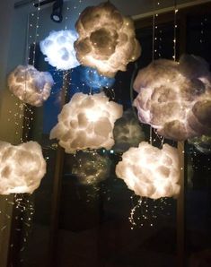 some clouds that are hanging from the ceiling in front of a window with lights on them