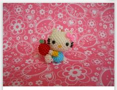 a hello kitty figurine holding a strawberry on a pink background with white flowers