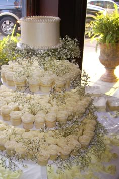 an image of a wedding cake with cupcakes on it and baby's breath flowers