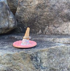 a small toy hat sitting on top of a pink plate next to some large rocks