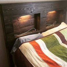 a bed that has two lights on each side of the headboard and is made out of wood