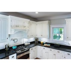 a kitchen with white cabinets and black counter tops is lit up by the light coming through the window