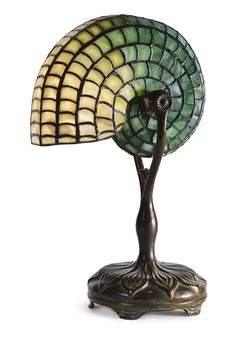 a lamp that is sitting on top of a stand with a green and yellow shade