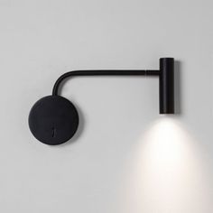 a black wall light mounted on the side of a white wall