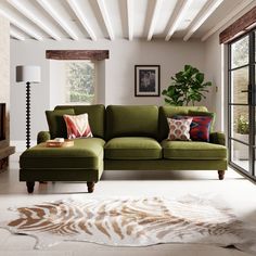 a living room with a large green couch and pillows on top of the rugs