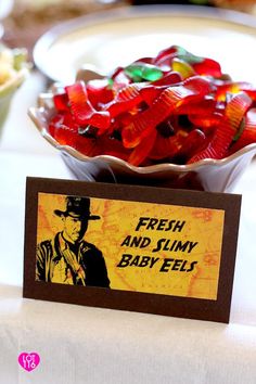 a bowl filled with gummy bears sitting on top of a table next to a sign that says fresh and slimy baby felts