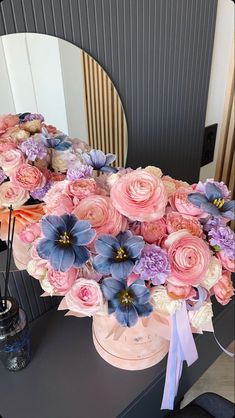 a vase filled with flowers sitting on top of a table next to a round mirror