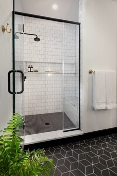 a bathroom with black and white tile flooring, a walk in shower and plants