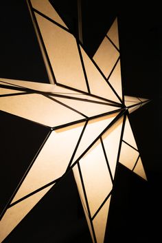 a large white star hanging from the ceiling with lights on it's sides and black background