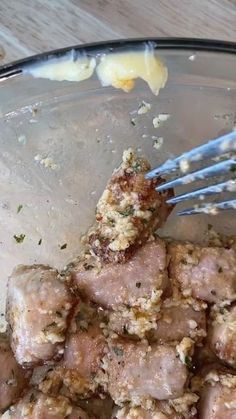 a glass bowl filled with meat and some blue utensils sticking out of it