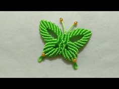 a green beaded butterfly sitting on top of a white surface