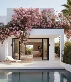 the pool is surrounded by pink flowers and greenery on the side of the house