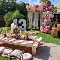 a table set up for a party with balloons, plates and decorations on the grass