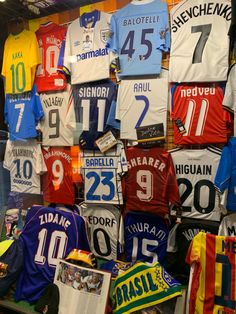 many different soccer jerseys are hanging on the wall