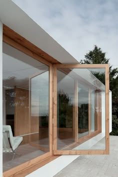 a white chair sitting on top of a patio next to a wooden structure with glass walls