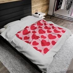 a bed with red hearts on it in a bedroom