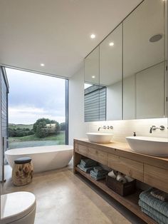 a large bathroom with two sinks and a bathtub in front of a huge window