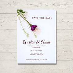 save the date card with purple flowers and greenery on white wood planks background