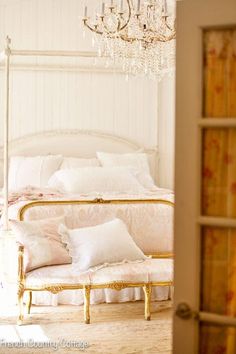 a bedroom with a bed, chandelier and pillows on it's headboard