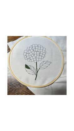 a white pillow with a flower embroidered on the front and back of it, sitting on top of a wooden table