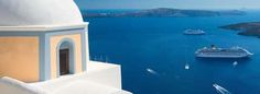 a cruise ship sailing in the ocean next to a white building with a blue roof